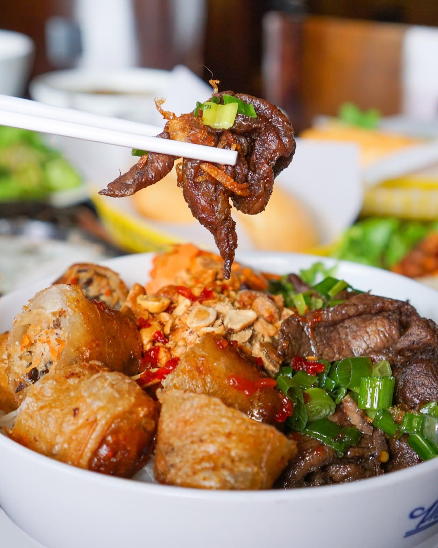 Vermicelli bowl with grilled beef, egg rolls, and crushed peanuts